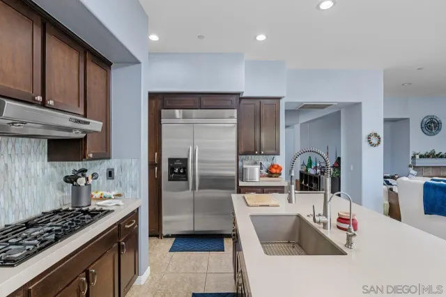 a kitchen with stainless steel appliances kitchen island granite countertop a sink stove and refrigerator