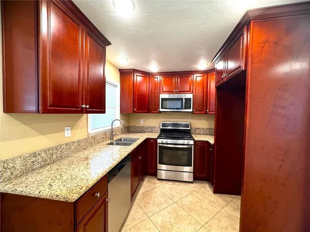 a kitchen with stainless steel appliances granite countertop wooden cabinets and granite counter tops