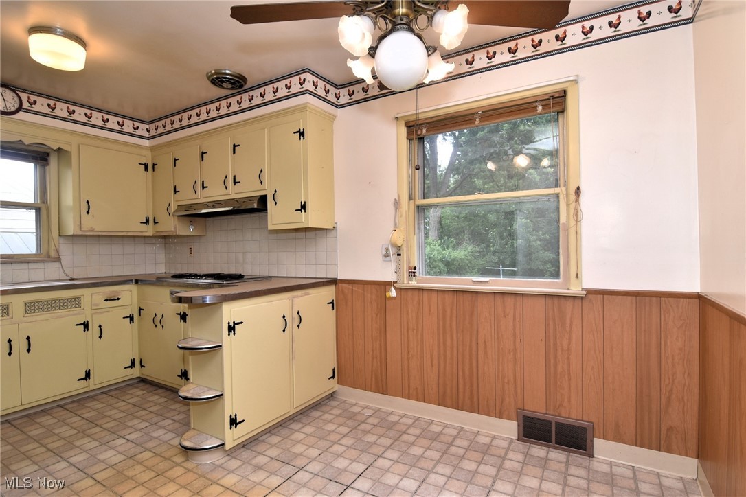 9421 David Road Cleveland, OH 44125 - Photo 11 of 36 Kitchen featuring a wainscoted wall, under cabinet range hood, plenty of natural light, cream cabinets, and light flooring