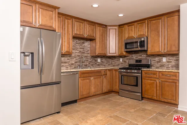 a kitchen with granite countertop a refrigerator stove top oven a sink and dishwasher