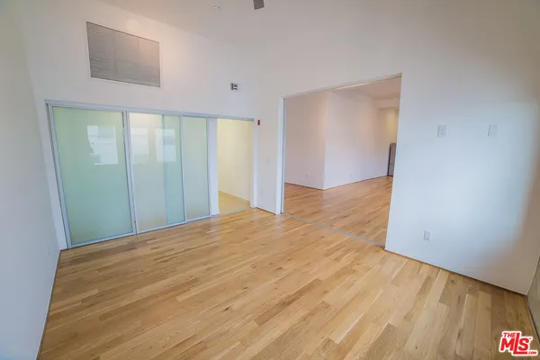 a view of empty room with wooden floor and fan