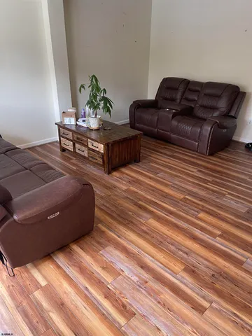 a living room with couches bookshelf and a stove with wooden floor