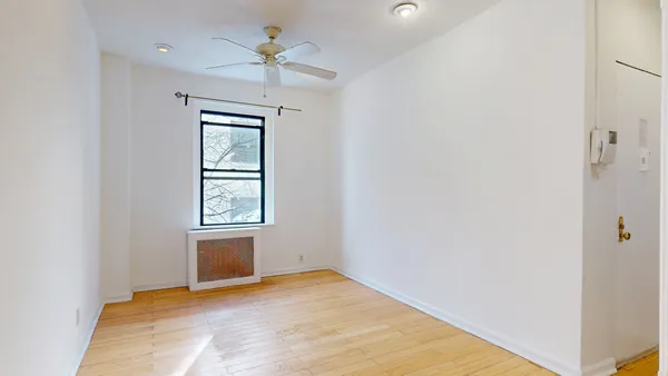 an empty room with chandelier fan and windows