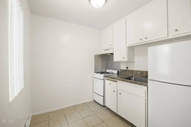a kitchen with granite countertop white cabinets and white appliances