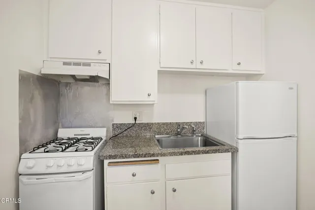 a kitchen with granite countertop cabinets and white stove top oven