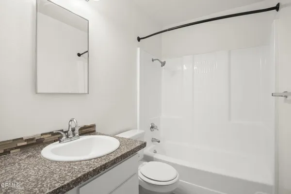 a bathroom with a granite countertop sink toilet a mirror and shower