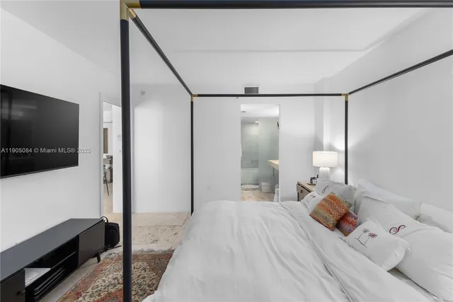 a bedroom with a bed and a flat tv screen on wall