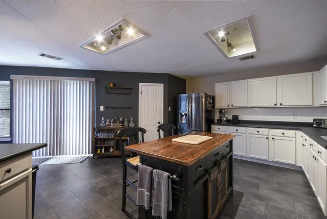 a kitchen with stainless steel appliances granite countertop a stove top oven a refrigerator a sink and chairs