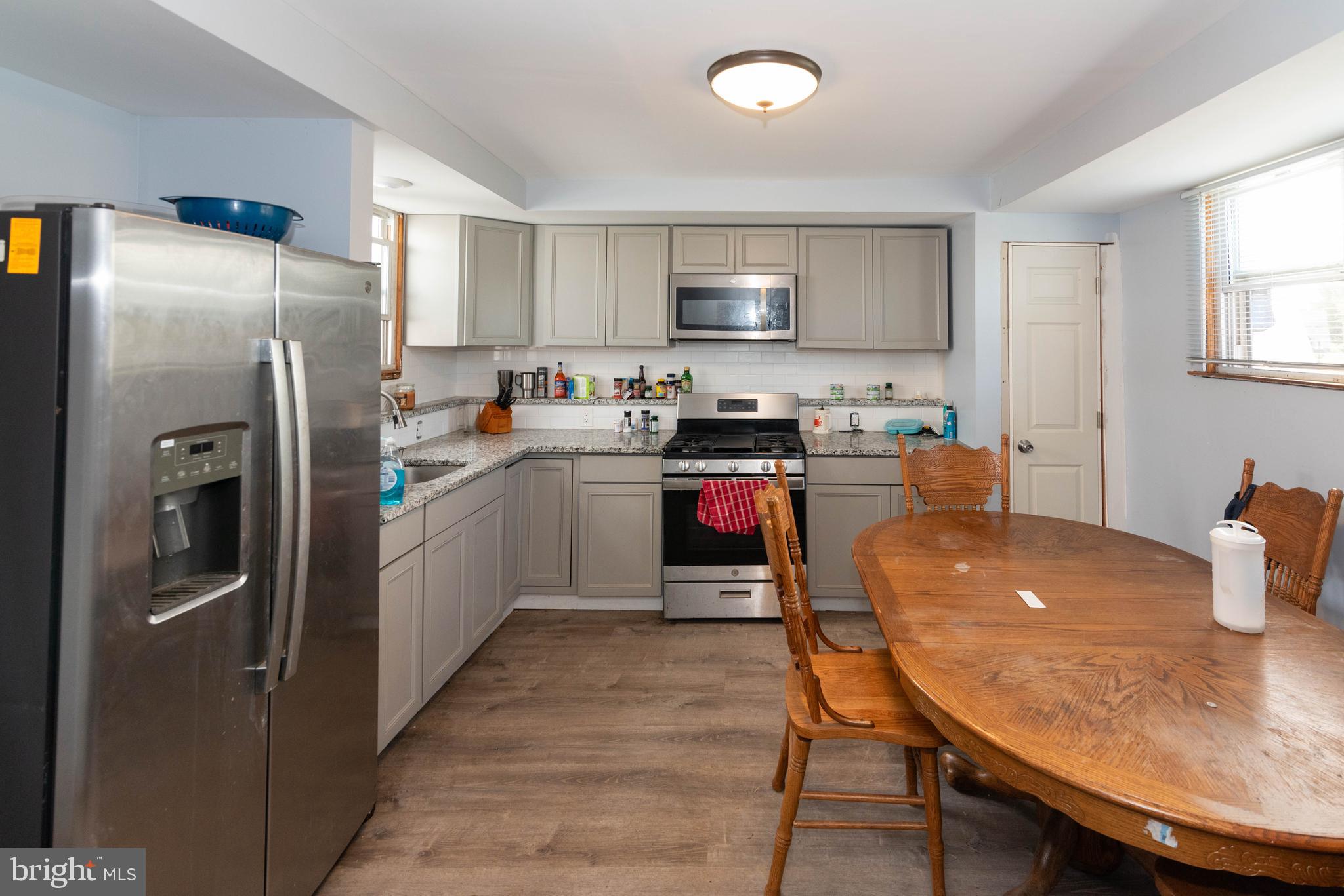 6510 North Point Road Edgemere, MD 21219 - Photo 35 of 56 a kitchen with stainless steel appliances granite countertop a stove a refrigerator a sink a dining table and chairs