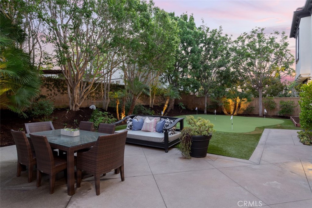 8 Madison Newport Beach, CA 92660 - Photo 27 of 34 a view of a patio with couches and a table and chairs with plants and trees