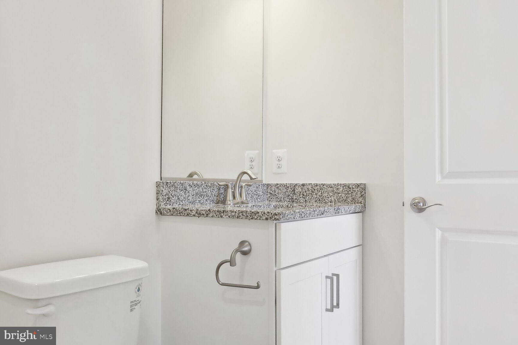 25017 Cypress Court Lewes, DE 19958 - Photo 4 of 14 a bathroom with a granite countertop toilet and a sink
