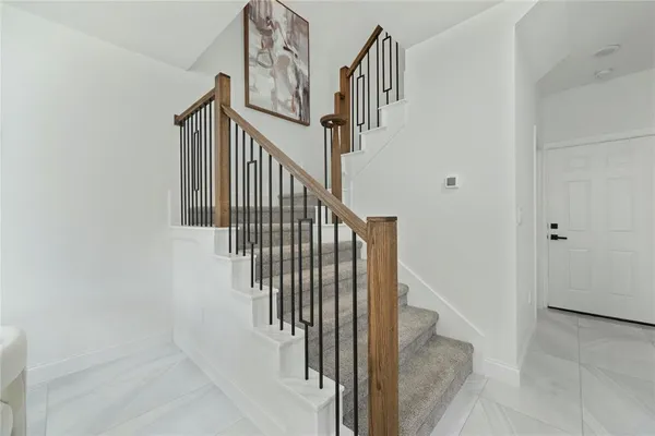 a view of staircase with railing and white walls