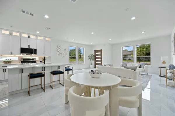a kitchen with stainless steel appliances kitchen island granite countertop a sink a stove a dining table and chairs