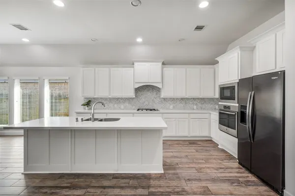 a kitchen with granite countertop a sink stainless steel appliances and cabinets