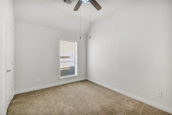 an empty room with windows and fan