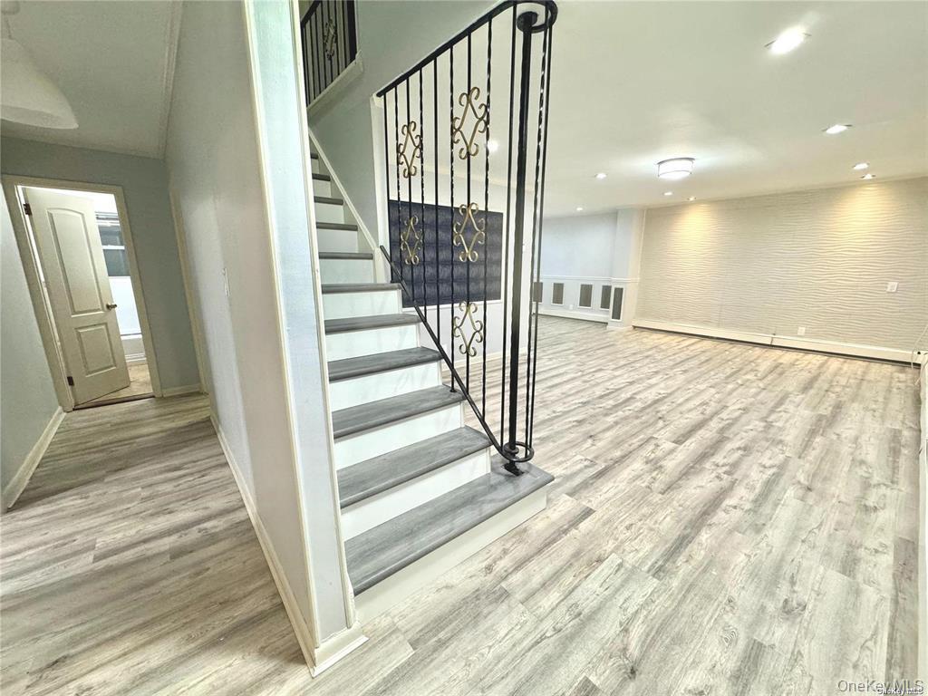 107 Baker Hill Road Great Neck, NY 11023 - Photo 4 of 33 Stairs featuring wood finished floors, brick wall, a baseboard radiator, and recessed lighting
