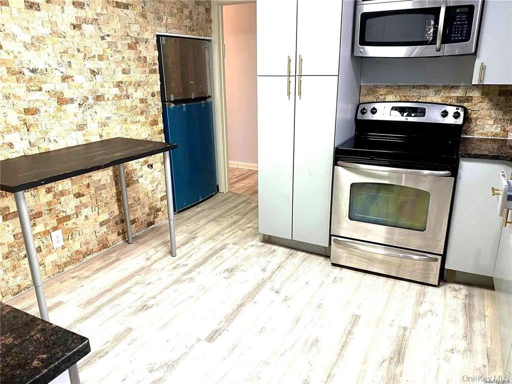 107 Baker Hill Road Great Neck, NY 11023 - Photo 7 of 29 a kitchen with a stove and a refrigerator