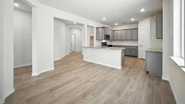 a large kitchen with a wooden floor and stainless steel appliances
