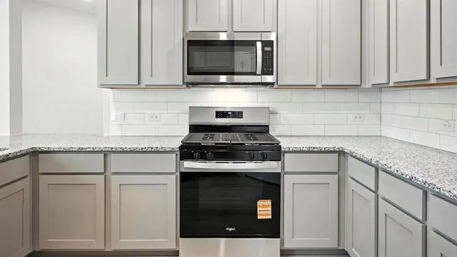 a kitchen with granite countertop white cabinets and a stove top oven
