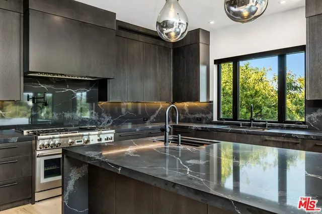 a kitchen with stainless steel appliances granite countertop a sink a stove counter space and a window