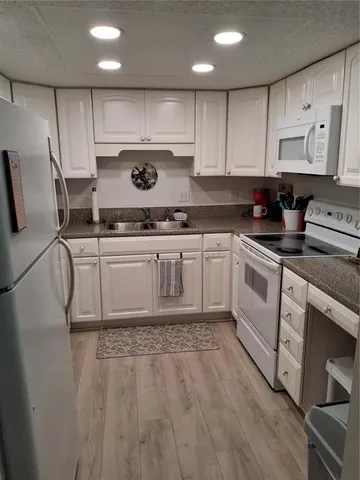 a kitchen with stainless steel appliances granite countertop a stove a sink a refrigerator and white cabinets