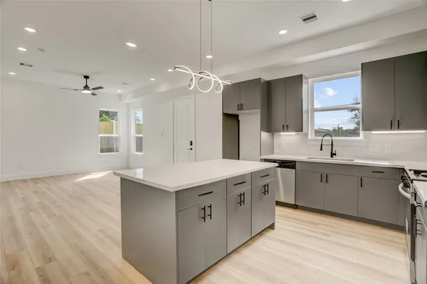 a kitchen with kitchen island a sink and a stove top oven with wooden floor