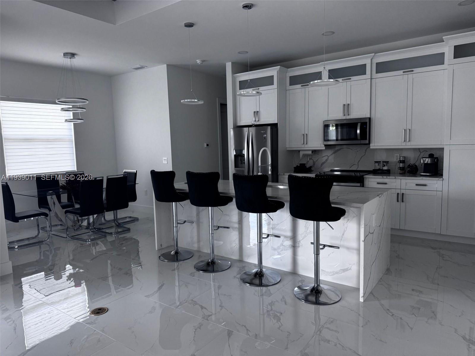 11 Connecticut Road Lehigh Acres, FL 33936 - Photo 3 of 11 a kitchen with stainless steel appliances kitchen island granite countertop a stove a sink a dining table and chairs