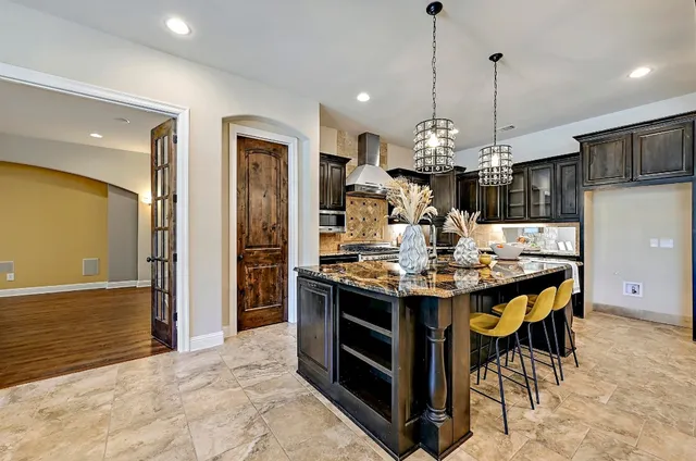 a kitchen with stainless steel appliances granite countertop a stove a refrigerator a kitchen island a dining table and chairs