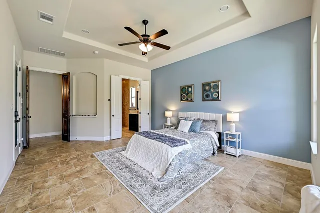 a spacious bedroom with a large bed and a chandelier