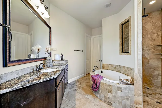 a bathroom with a granite countertop tub sink and mirror