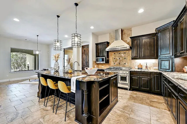 a kitchen with stainless steel appliances granite countertop a stove a sink dishwasher a refrigerator and a wooden cabinets