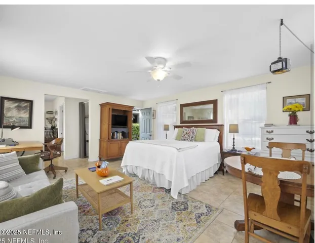 a spacious bedroom with a bed a couch and a dresser with wooden floor