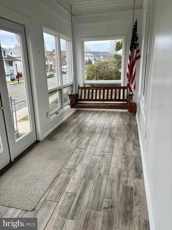 a view of an empty room with wooden floor and windows