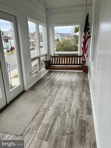 a view of an empty room with wooden floor and windows