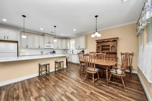 a kitchen with stainless steel appliances kitchen island granite countertop a dining table chairs sink and cabinets