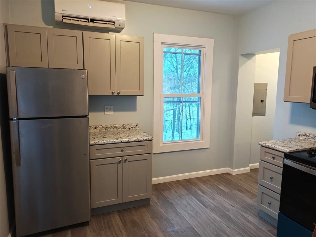115 Maple Street, Unit 3 Gardner, MA 01440 - Photo 2 of 12 a kitchen with granite countertop a refrigerator a sink dishwasher a stove and white countertops with wooden floor