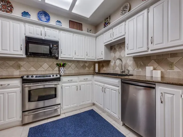 a kitchen with granite countertop white cabinets stainless steel appliances and a sink