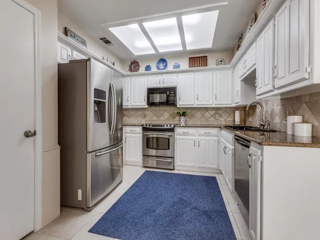 a kitchen with stainless steel appliances granite countertop a refrigerator a stove a sink and a microwave