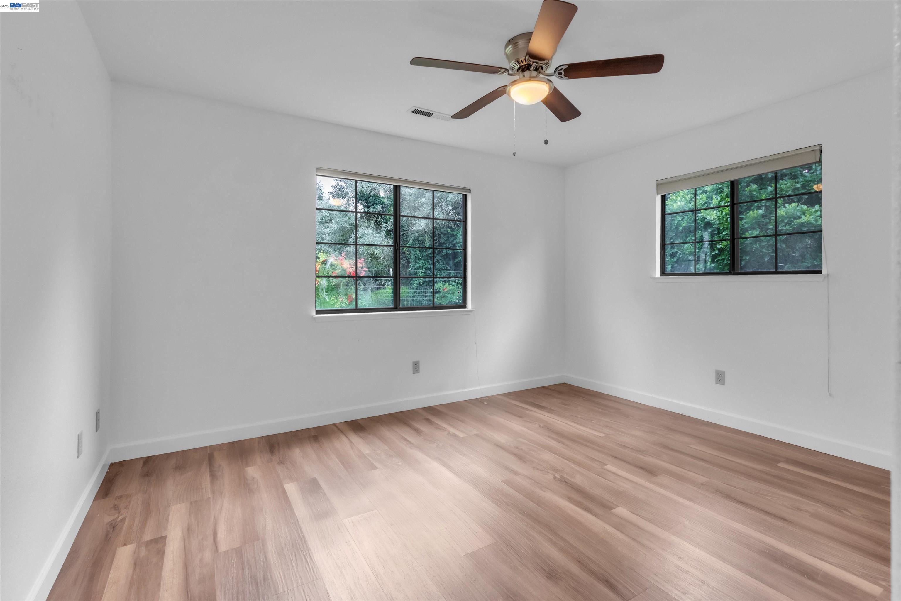 3665 Illinois Avenue Corning, CA 96021 - Photo 40 of 54 an empty room with wooden floor ceiling fan and windows