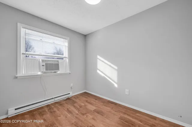 a view of an empty room with a window and wooden floor