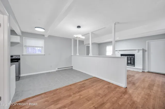 an empty room with wooden floor and a kitchen
