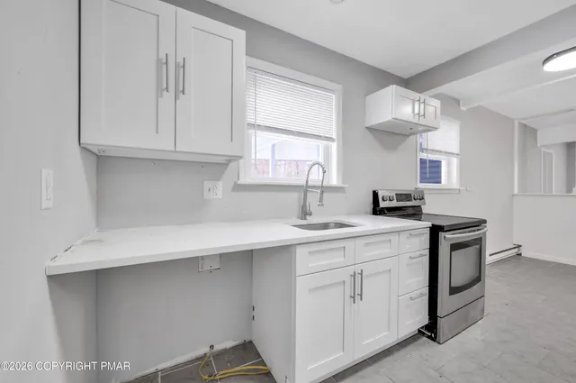 a kitchen with white cabinets and sink