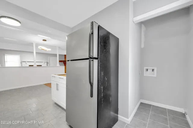 a view of a kitchen with refrigerator and white cabinets
