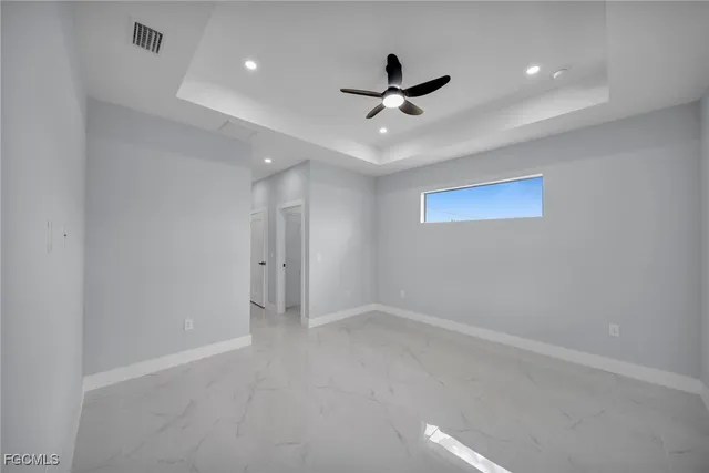 an empty room with ceiling fan and windows