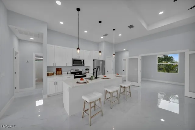 a kitchen with stainless steel appliances a refrigerator a stove a sink a dining table and chairs