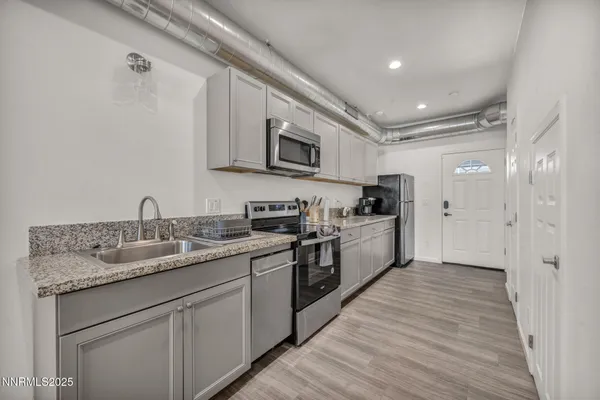 a kitchen with stainless steel appliances granite countertop a sink and dishwasher a stove top oven with wooden floor