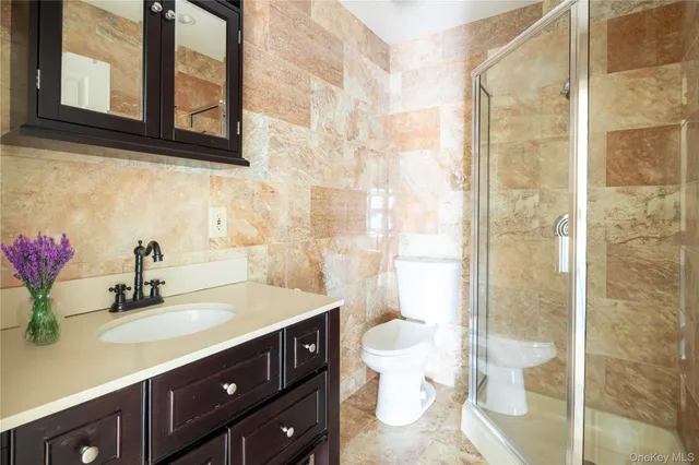 a bathroom with a sink vanity granite toilet and shower
