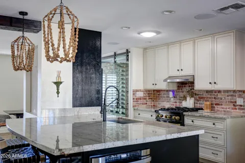 a kitchen with stainless steel appliances kitchen island granite countertop a table chairs and a refrigerator