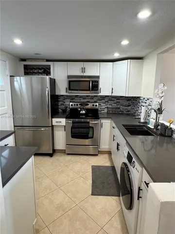 a kitchen with stainless steel appliances granite countertop a refrigerator a stove and a sink