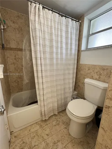 a white toilet sitting next to a shower curtain
